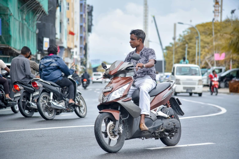 a man riding a motorcycle down a street near another motor bike