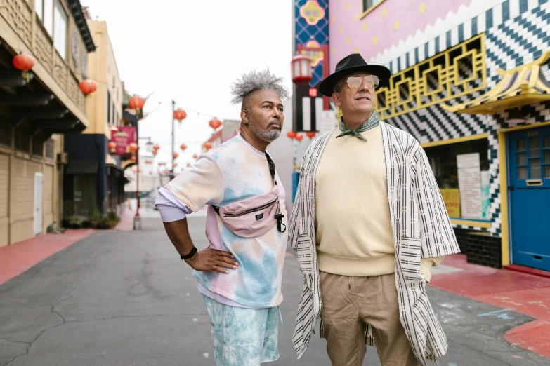 two older gentlemen are posing on the side of the street