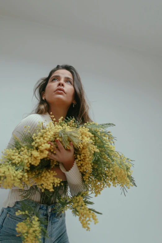 a woman holding some yellow flowers in her hand