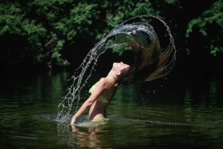 a young child splashing water on their head in a lake