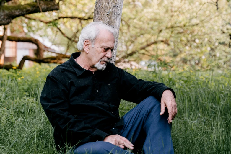 man in black shirt sitting under a tree