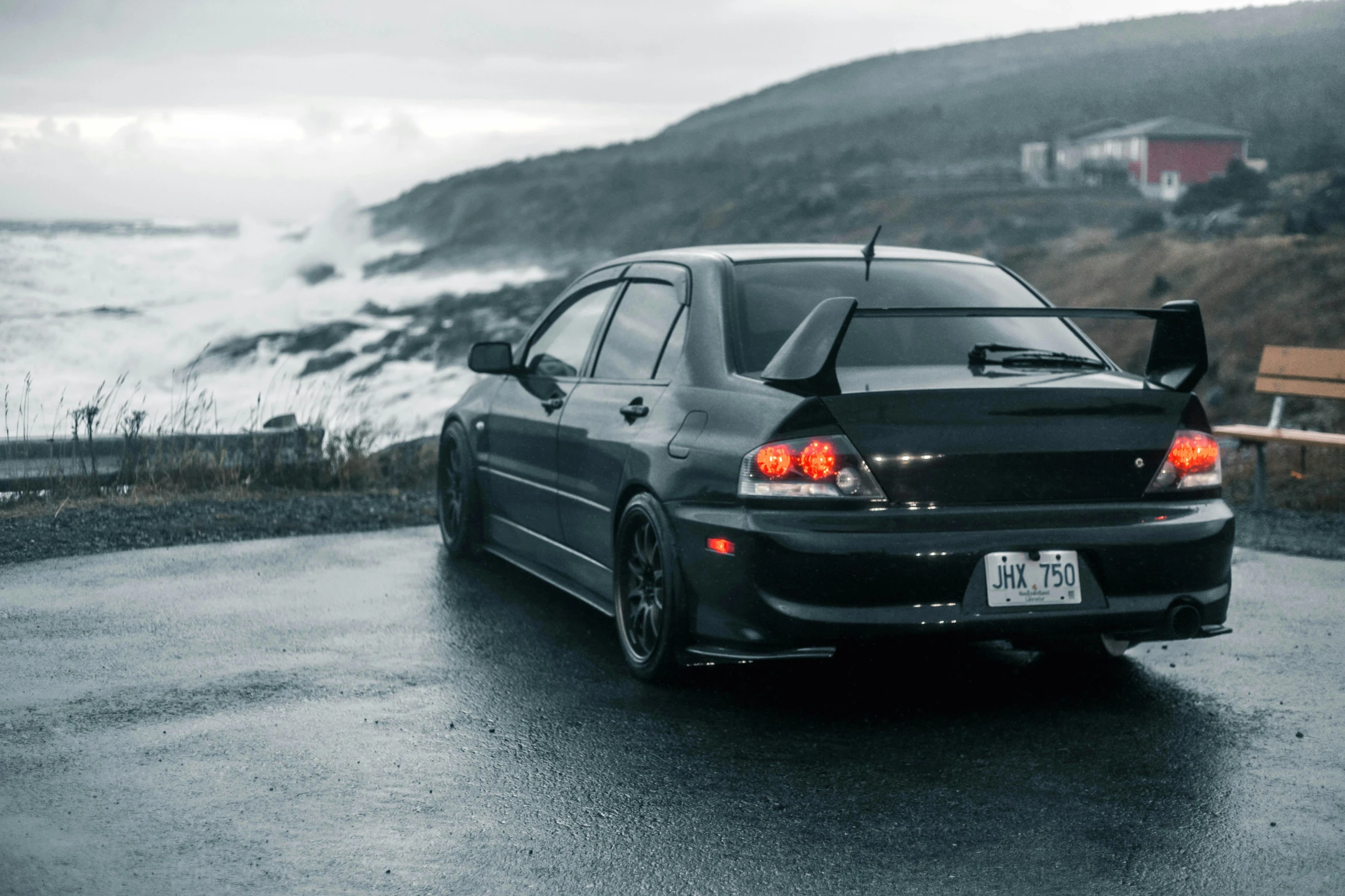 a black car driving on a road near a beach