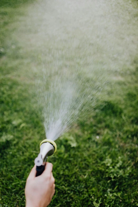 a person uses a sprinkle hose to clear the lawn