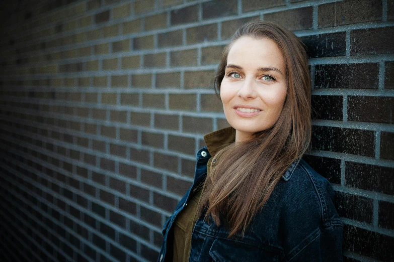 woman in front of a brick wall, wearing a blue coat