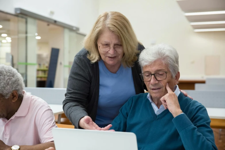 three people sitting in front of laptops while one looks at the screen