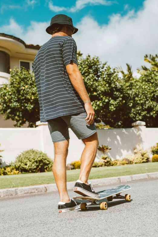 an older man in blue shirt standing on skateboard in street