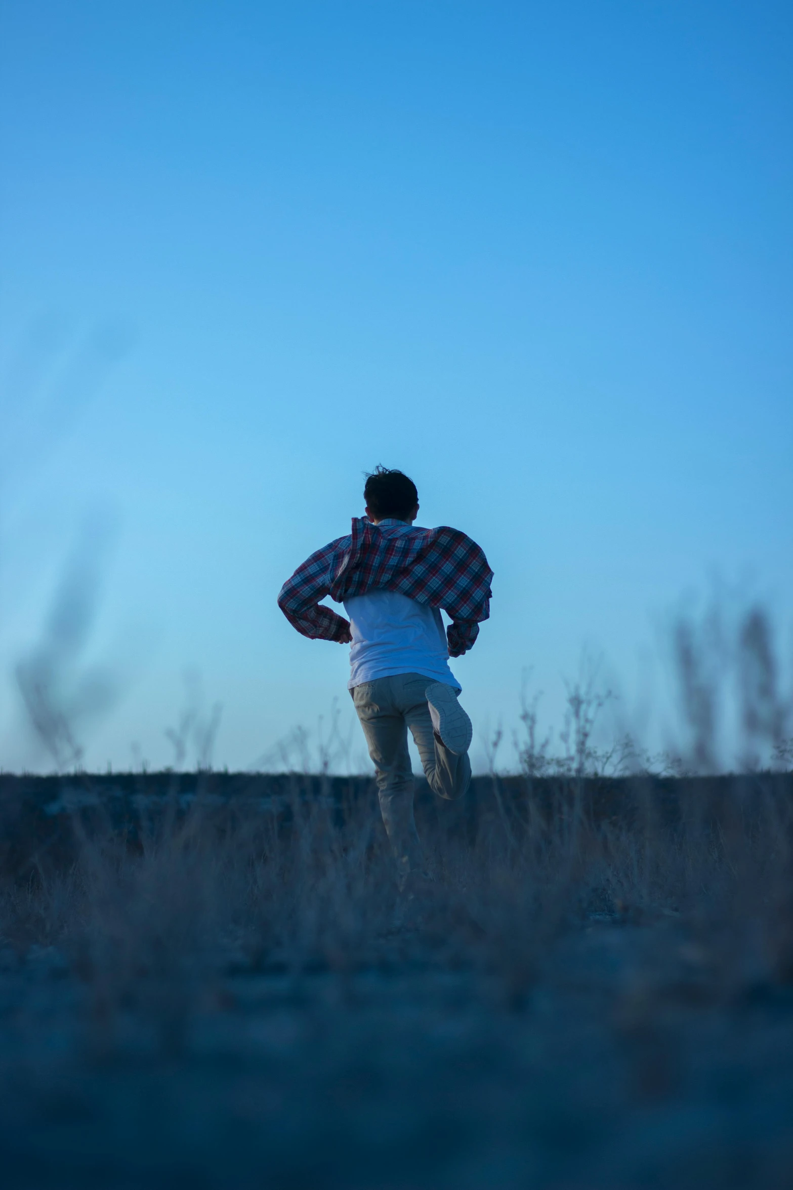 a man walking across a dry grass field