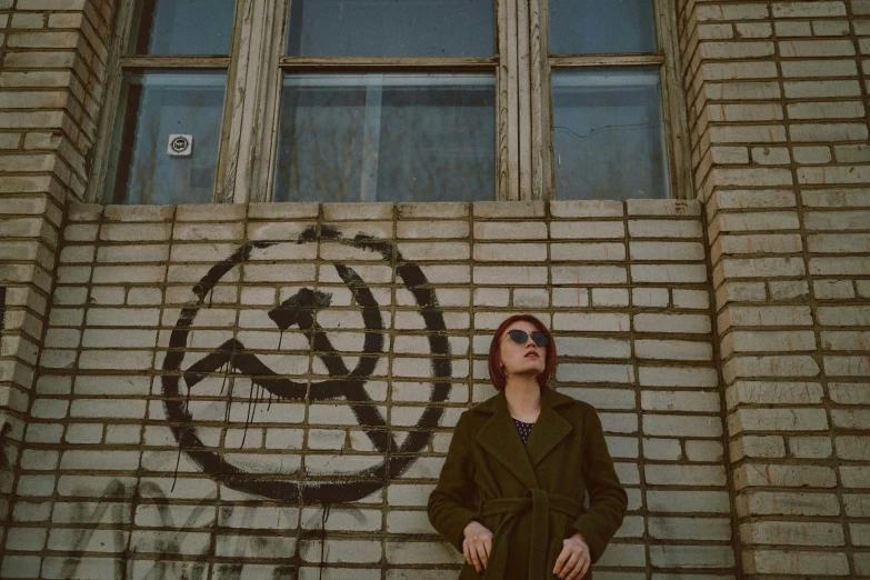 a man standing in front of a brick wall with a drawn circle