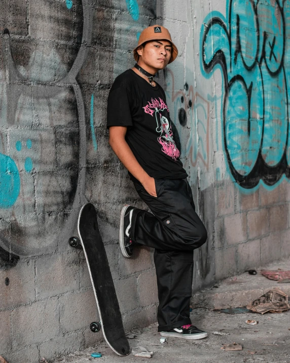 a boy is leaning against the wall with his skateboard