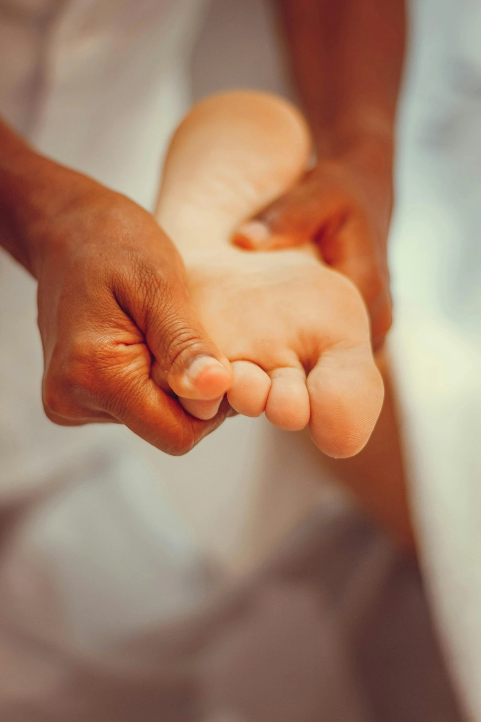 an infant holding onto the thumb of its mother