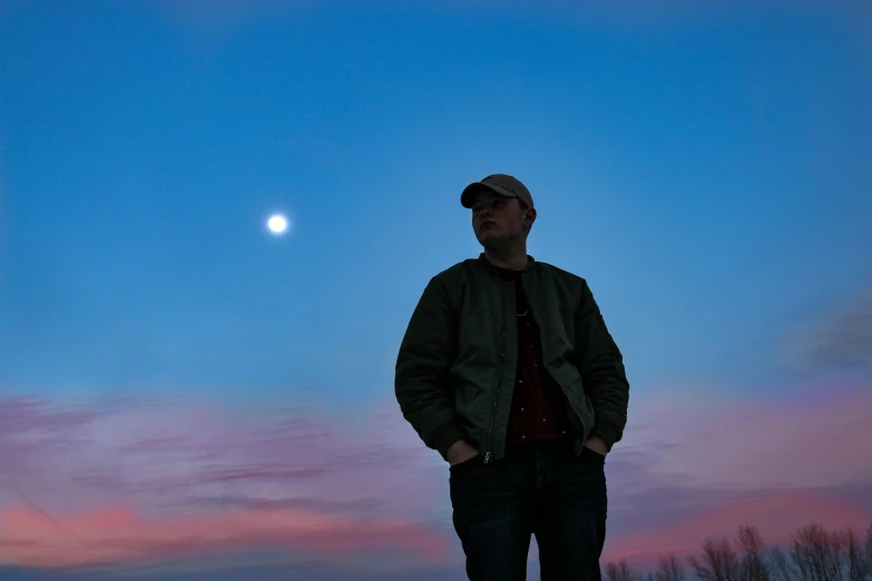 man posing with a full moon in the distance