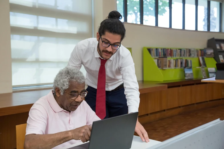 a man helping an elderly woman with a laptop