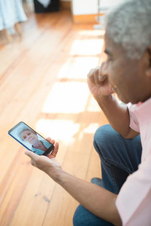 an old man on a cell phone is holding a picture