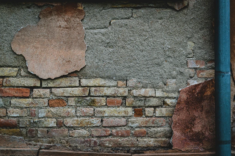 a cement wall with a rusted sign on it