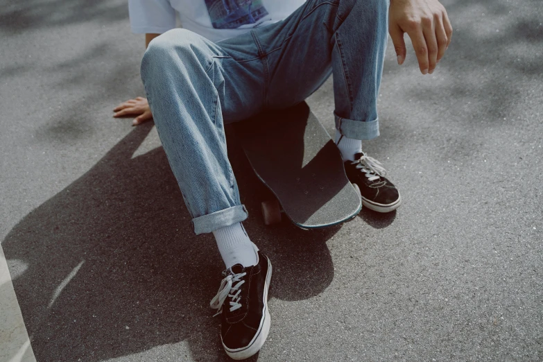 a skateboarder sits on the street with his sneakers on
