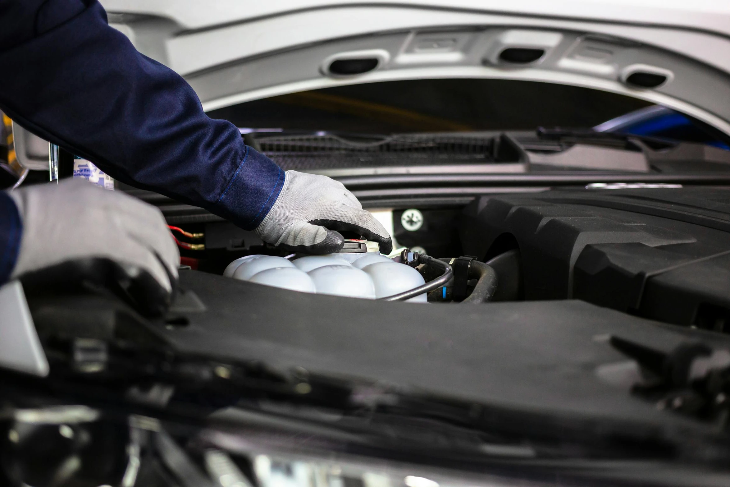 person wearing gloves working on an engine of a vehicle