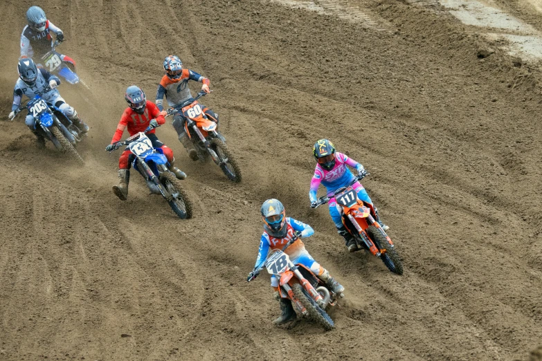 dirt bikers on various teams going down a dirt track