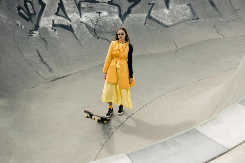 a woman standing with her skateboard in an empty swimming pool