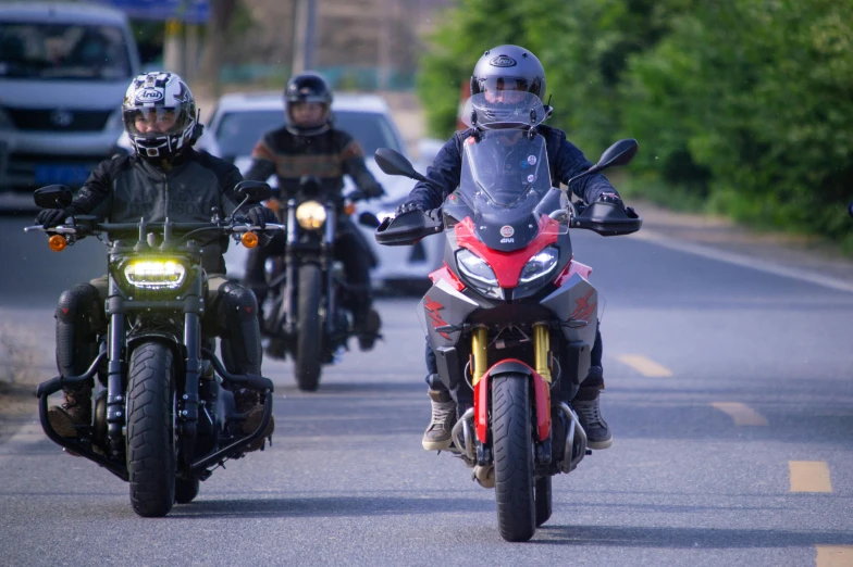 a line of bikers with helmets going down a road