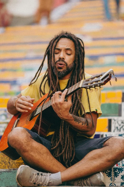 a man is sitting on a ledge playing the guitar