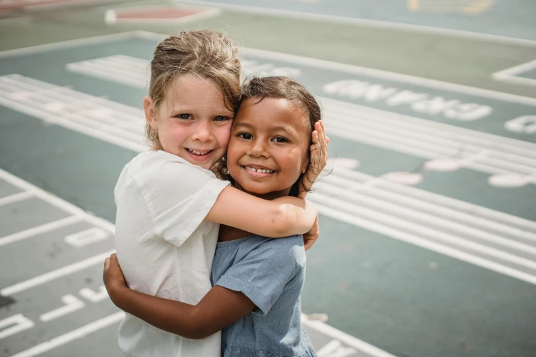 two small children hugging and smiling outside an airport