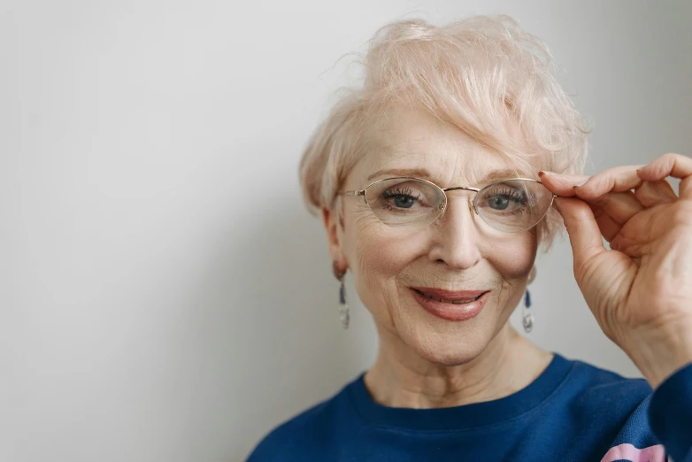 an elderly woman smiling, holding her glasses