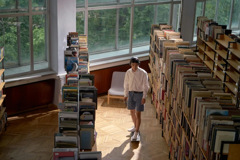 a young man is standing among books at the liry