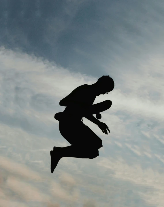 silhouette of man with shoe on in mid air against cloudy sky