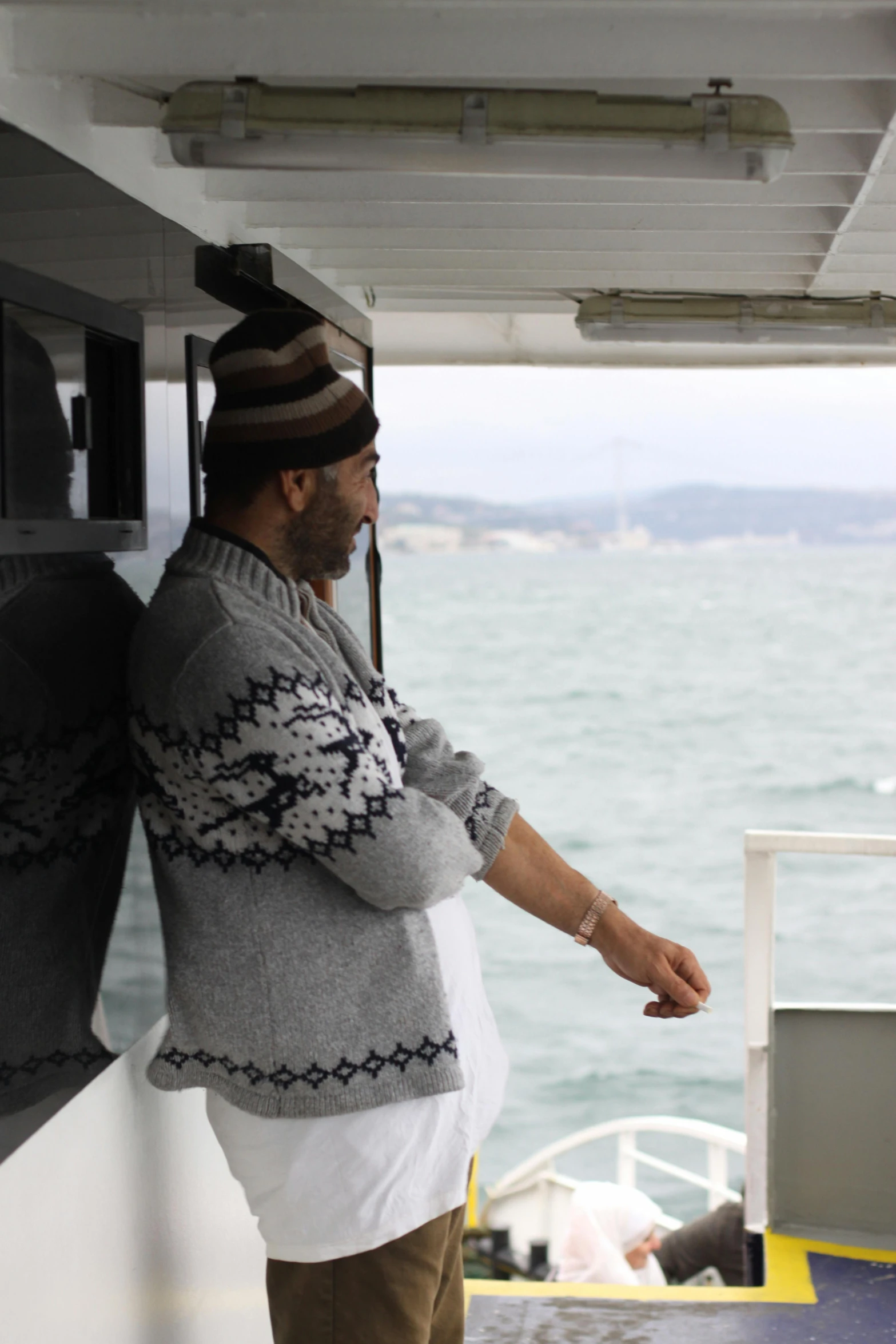 a man stands on the back of a ferry boat looking out over the water