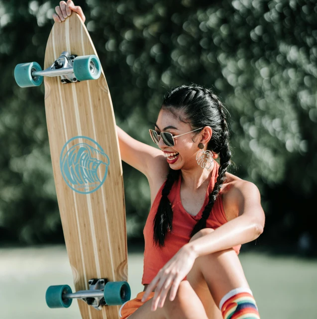 a girl sitting and smiling as she holds a skateboard