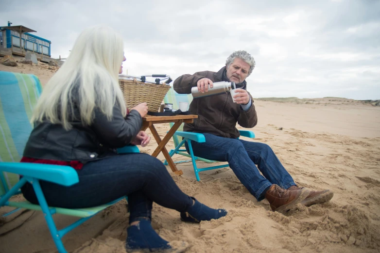 a man sitting at a table on a beach with a woman