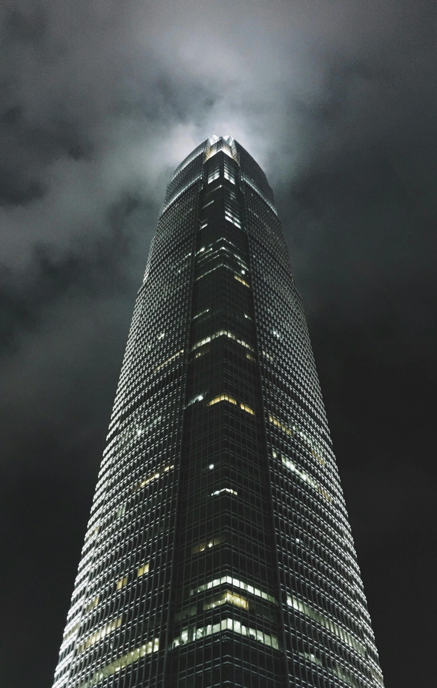 dark night sky and large building with lights reflecting in glass