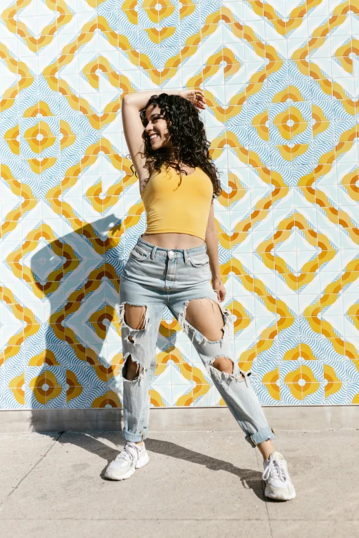 a woman in ripped jeans standing next to a wall