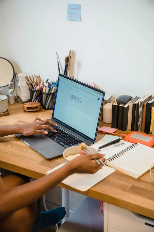 a man sitting at a desk typing on a laptop