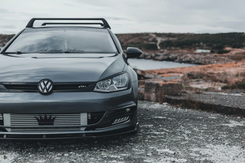 a gray volkswagen polo gtv parked in front of a lake