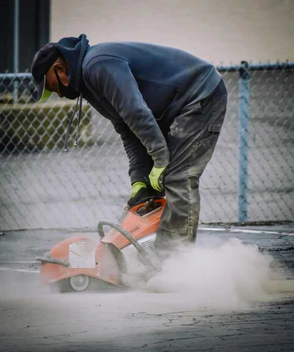 man with a gas powered saw  into some concrete