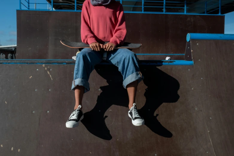 a man sitting on a wall, using his skateboard