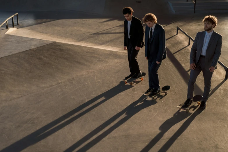 three boys wearing suits riding skateboards in an indoor ramp