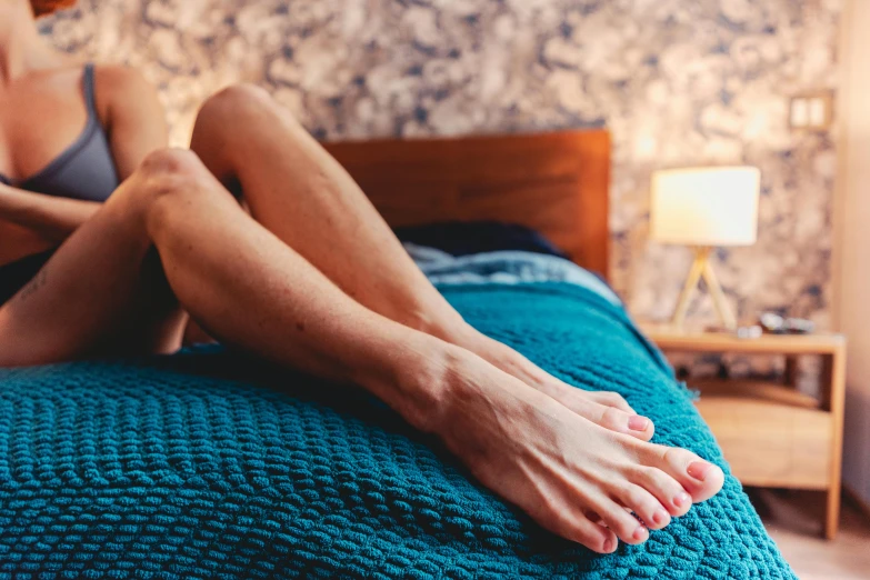 the bare feet are resting on the green bed