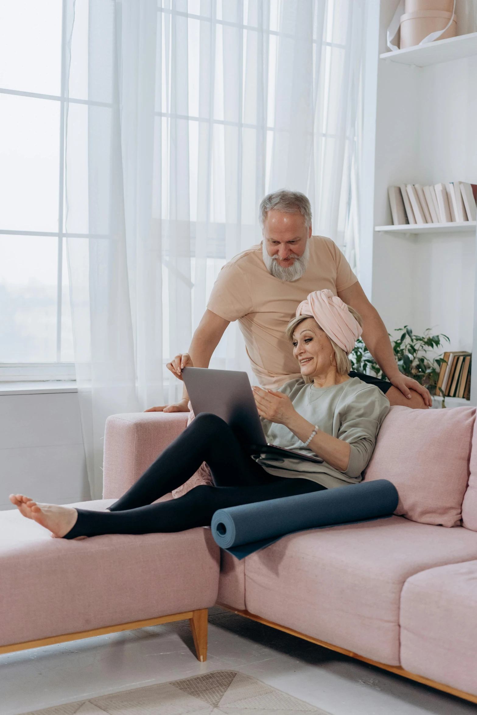 an older man standing next to a woman using a laptop