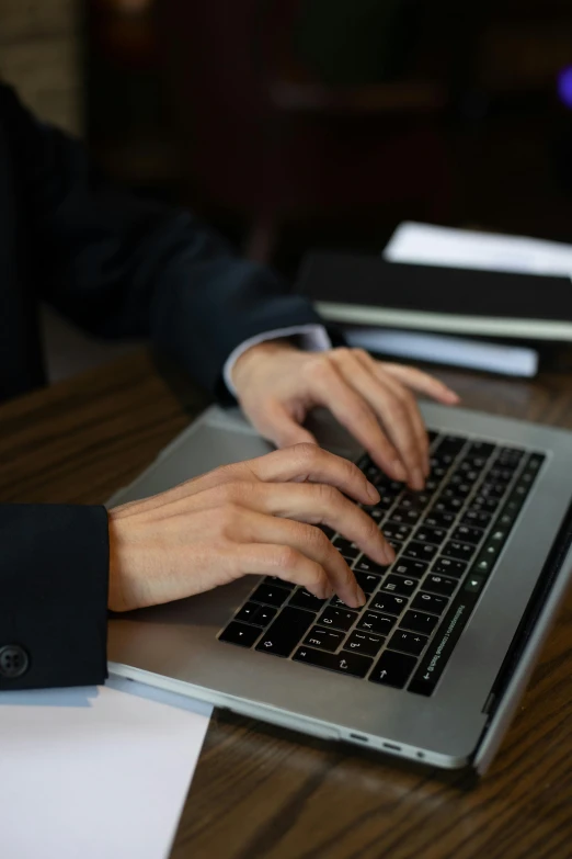 a person typing on a laptop computer with a cup of coffee on the table