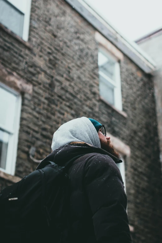 a person in black jacket near building and windows