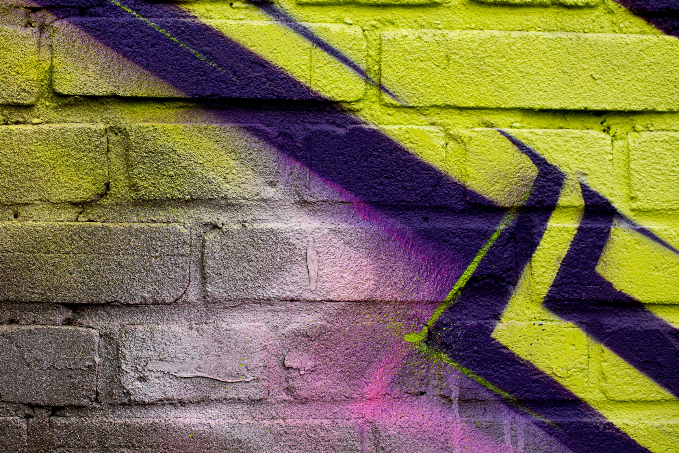 a graffiti mural on a wall that has purple and yellow paint