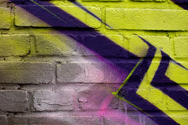 a graffiti mural on a wall that has purple and yellow paint