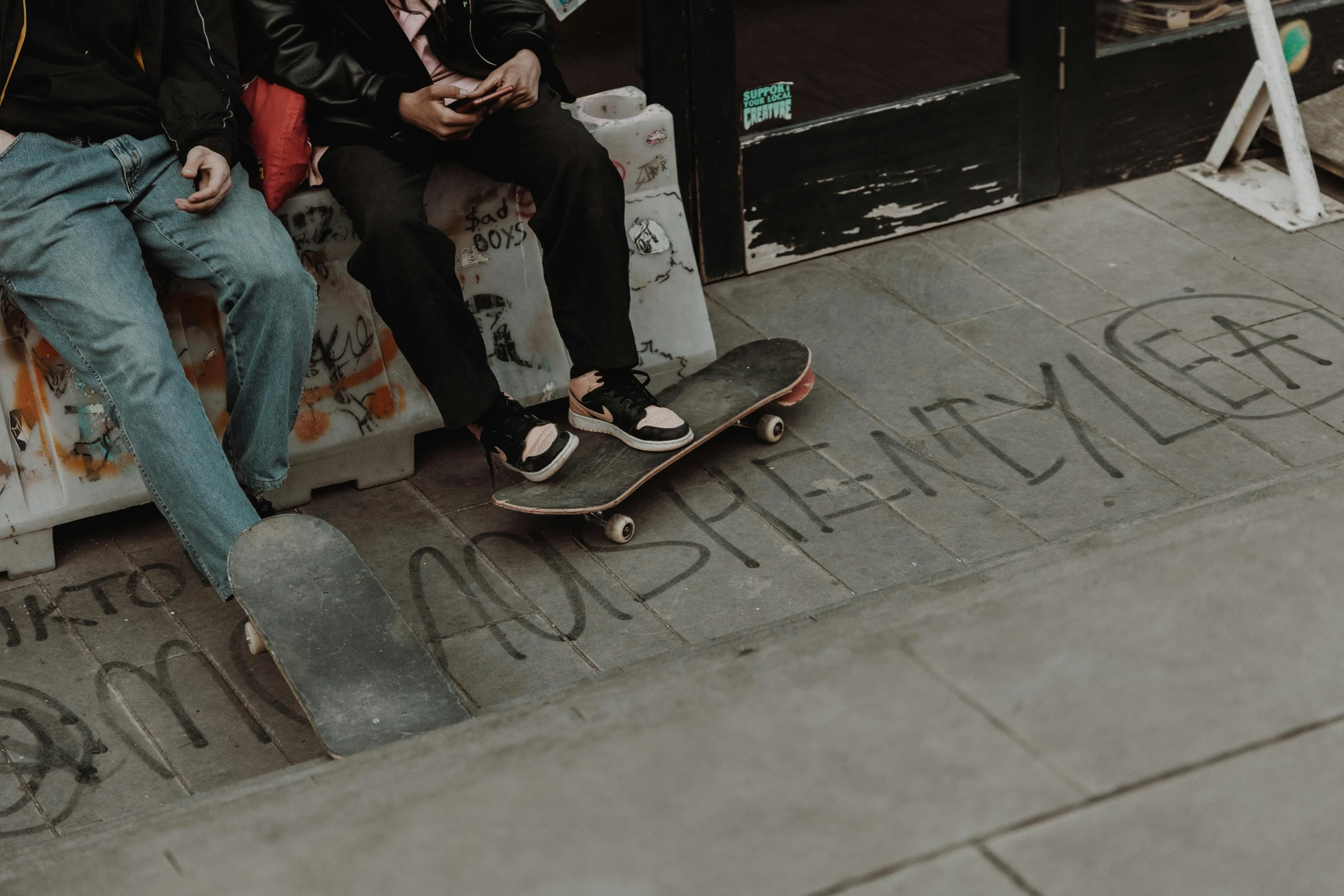 two guys sitting down together on their skateboards