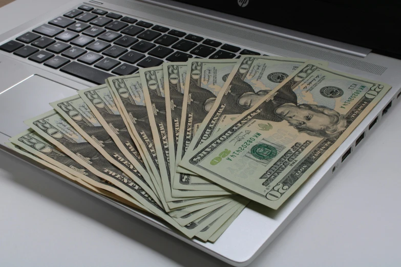 laptop keyboard displaying an image of twenty dollar bills