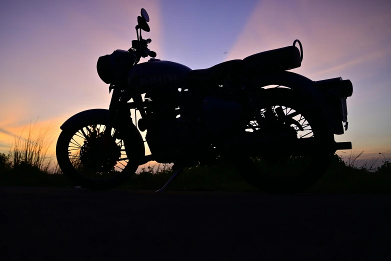 a motorcycle parked on a road near the sun