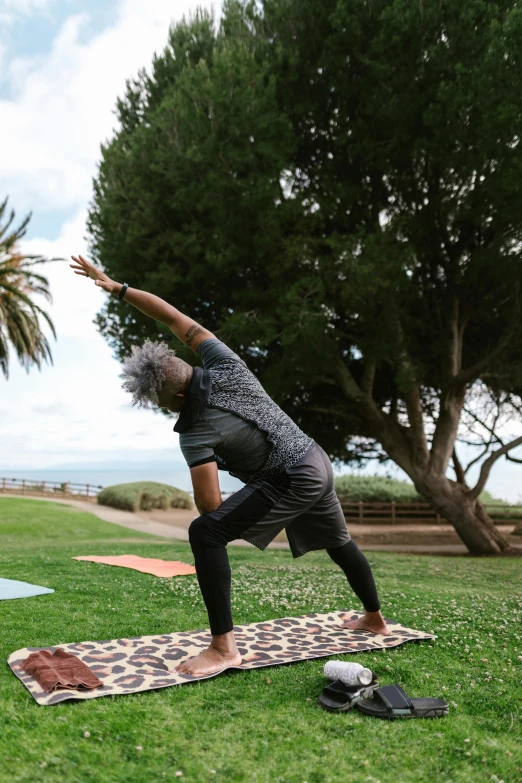 a man does yoga in a field with grass and trees