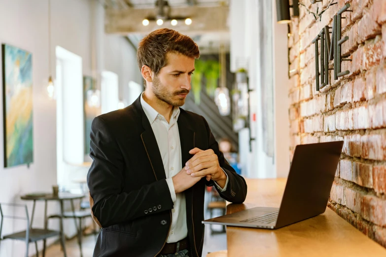 a man adjusting his suit in front of a laptop