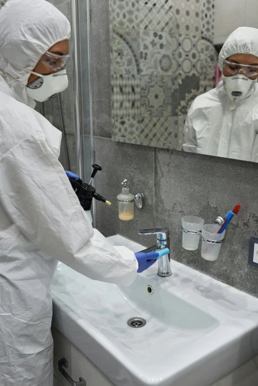 a person wearing a white hazmat and standing near a sink